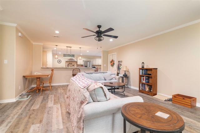 living room with crown molding, ceiling fan, and light wood-type flooring