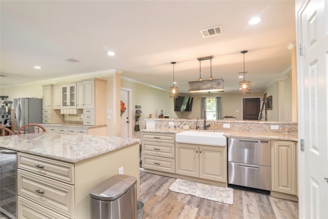 kitchen with light hardwood / wood-style flooring, appliances with stainless steel finishes, sink, a kitchen island, and a breakfast bar