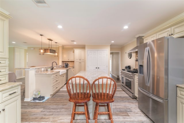 kitchen with light stone countertops, light hardwood / wood-style flooring, stainless steel appliances, and an island with sink