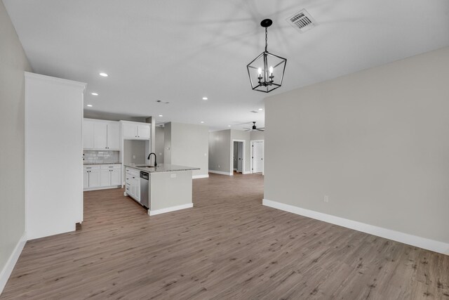 kitchen featuring ceiling fan with notable chandelier, an island with sink, sink, light wood-type flooring, and white cabinets