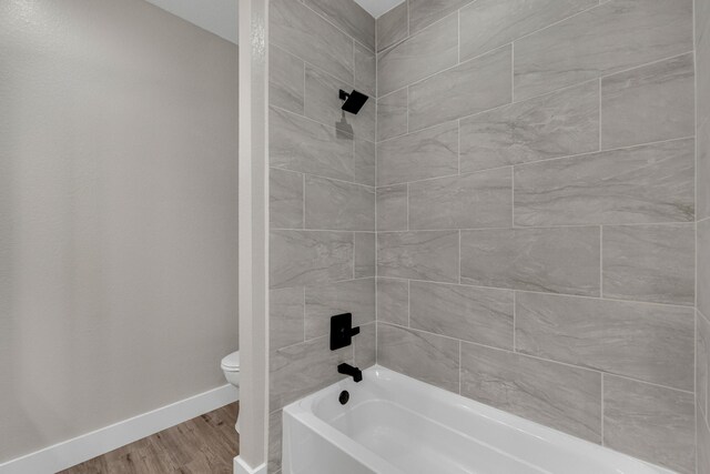 bathroom with toilet, wood-type flooring, and tiled shower / bath