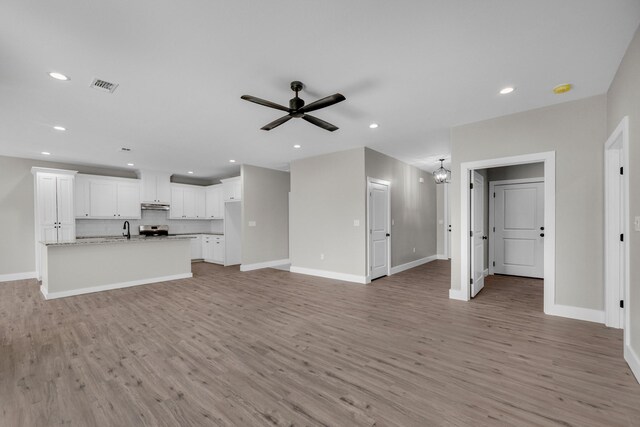 unfurnished living room featuring light wood-type flooring, ceiling fan with notable chandelier, and sink