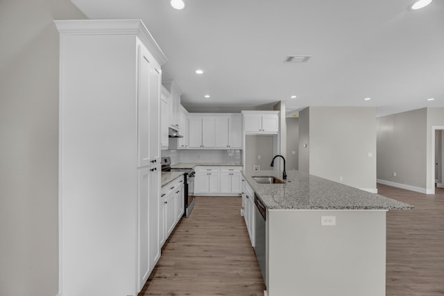 kitchen with light hardwood / wood-style flooring, appliances with stainless steel finishes, white cabinetry, sink, and a center island with sink