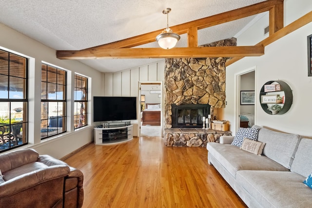 living room with a textured ceiling, a fireplace, light wood-type flooring, and lofted ceiling with beams