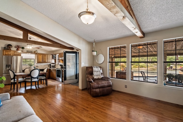 living room with a wealth of natural light, ceiling fan, hardwood / wood-style flooring, and a textured ceiling