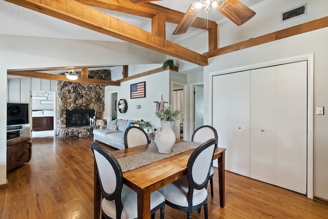 dining room featuring a fireplace, lofted ceiling, hardwood / wood-style flooring, and ceiling fan