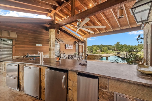 view of patio / terrace featuring a bar, exterior kitchen, and ceiling fan