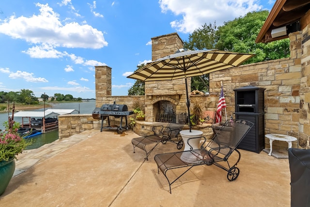 view of patio / terrace with an outdoor stone fireplace, area for grilling, and a water view