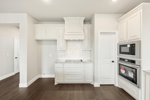 kitchen with oven, light stone countertops, premium range hood, black microwave, and dark hardwood / wood-style floors