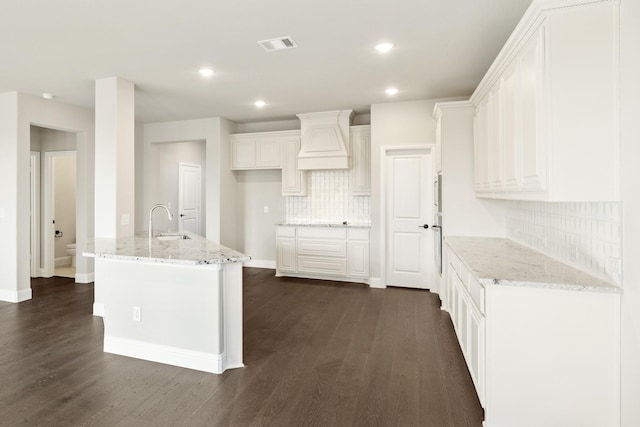 kitchen featuring backsplash, white cabinets, and light stone counters