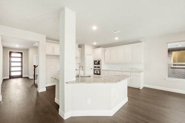 kitchen featuring light stone countertops, white cabinets, stainless steel oven, and built in microwave