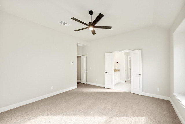 unfurnished bedroom with light colored carpet, vaulted ceiling, ensuite bath, and ceiling fan