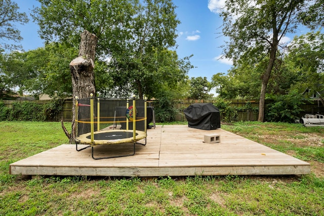 deck featuring a trampoline, grilling area, and a yard