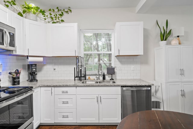 kitchen featuring light stone counters, sink, appliances with stainless steel finishes, and white cabinetry