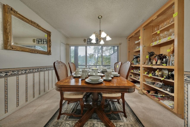 carpeted dining room with a notable chandelier and a textured ceiling