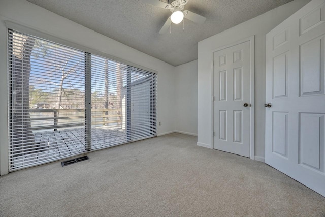 unfurnished bedroom with light carpet, a textured ceiling, and ceiling fan