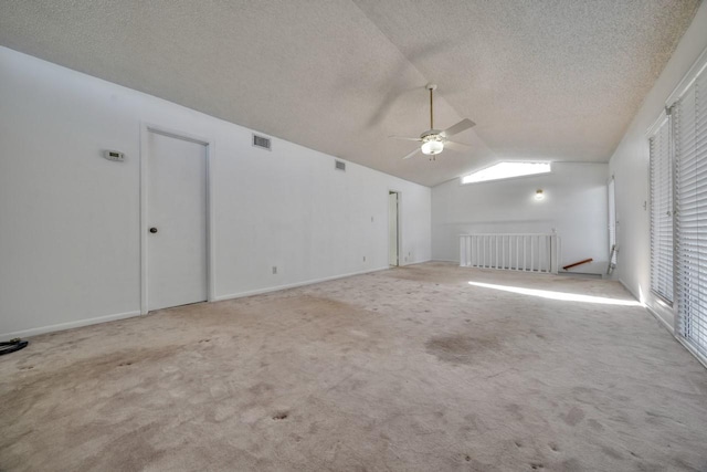 carpeted spare room featuring ceiling fan, radiator, vaulted ceiling, and a textured ceiling