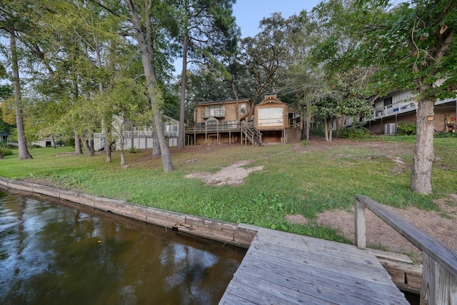 dock area featuring a deck with water view and a yard