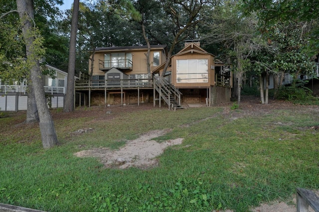 rear view of house with a wooden deck and a yard