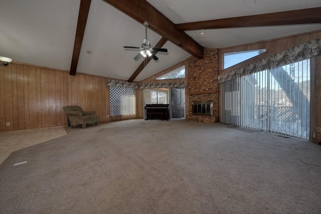 unfurnished living room with plenty of natural light, lofted ceiling with beams, wood walls, and carpet