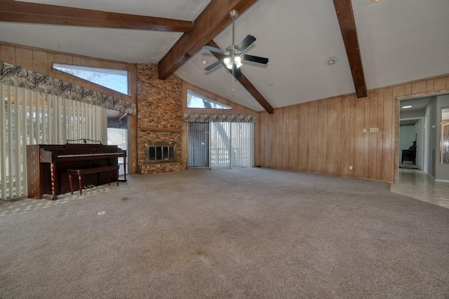 unfurnished living room with carpet, high vaulted ceiling, beam ceiling, and wood walls