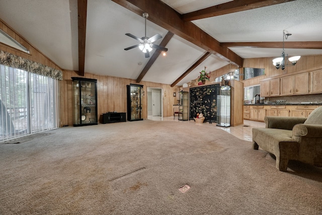 unfurnished living room featuring sink, wood walls, vaulted ceiling with beams, a textured ceiling, and light carpet