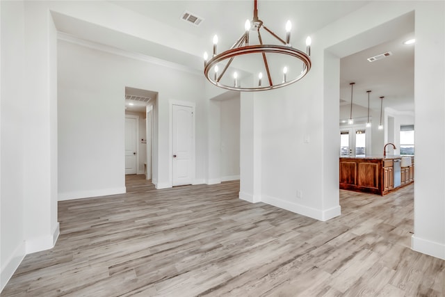 unfurnished dining area featuring a notable chandelier, sink, and light hardwood / wood-style flooring