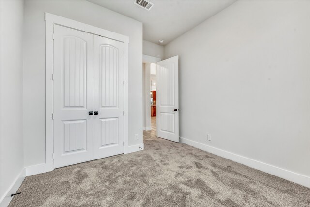 unfurnished bedroom featuring a closet and light colored carpet