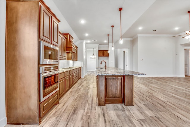 kitchen featuring stainless steel appliances, sink, light hardwood / wood-style flooring, hanging light fixtures, and a large island