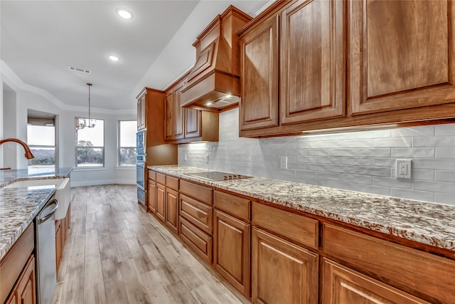 kitchen with light stone countertops, an inviting chandelier, light hardwood / wood-style flooring, decorative light fixtures, and decorative backsplash