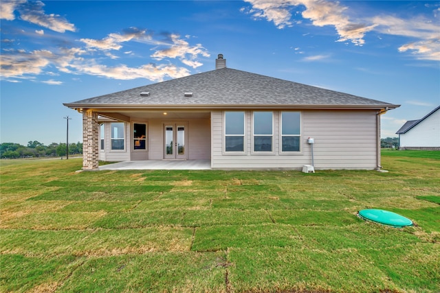 back of property with a lawn, french doors, and a patio