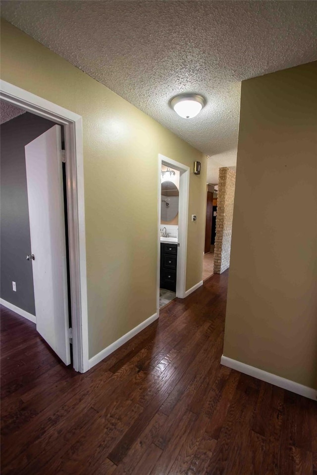 unfurnished bedroom with dark wood-type flooring, a textured ceiling, a closet, and multiple windows