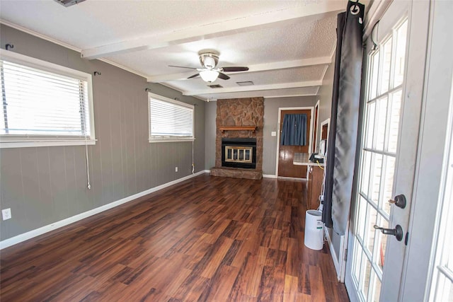 empty room featuring ceiling fan, dark hardwood / wood-style floors, beam ceiling, and a wealth of natural light