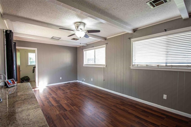 unfurnished living room with beamed ceiling, a textured ceiling, a fireplace, dark hardwood / wood-style flooring, and ceiling fan