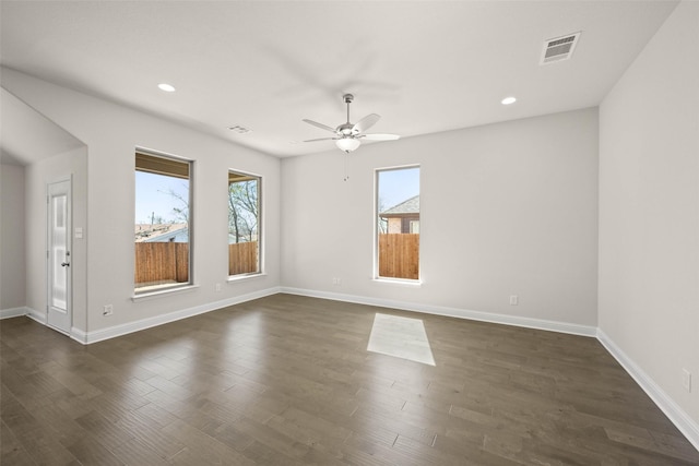 empty room with dark wood-style floors, a healthy amount of sunlight, and visible vents