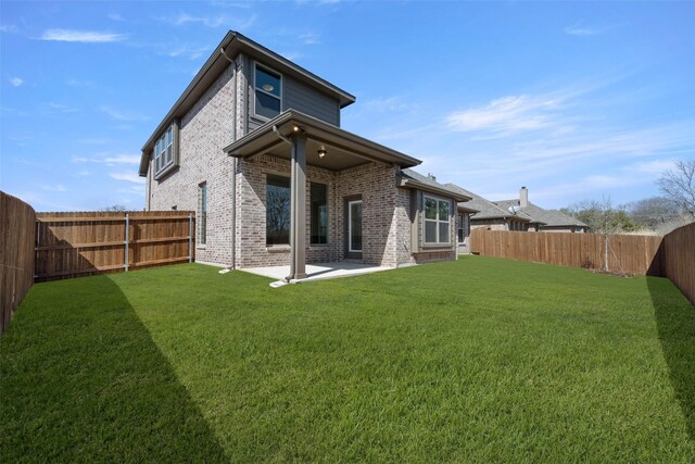 rear view of house featuring a patio, a yard, a fenced backyard, and brick siding