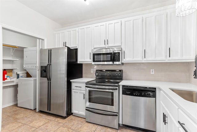 kitchen with white cabinets, sink, stacked washing maching and dryer, appliances with stainless steel finishes, and tasteful backsplash