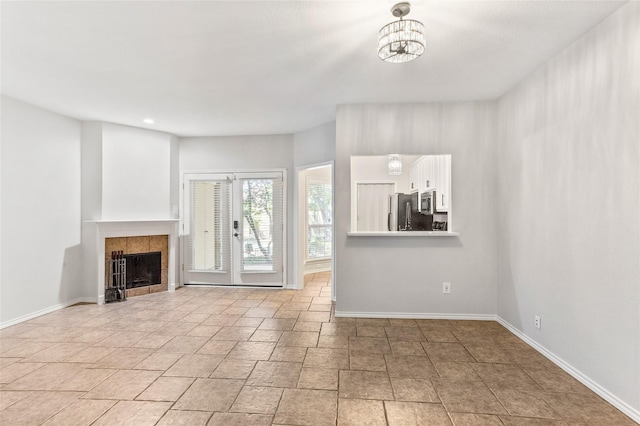 unfurnished living room with a tile fireplace and a chandelier