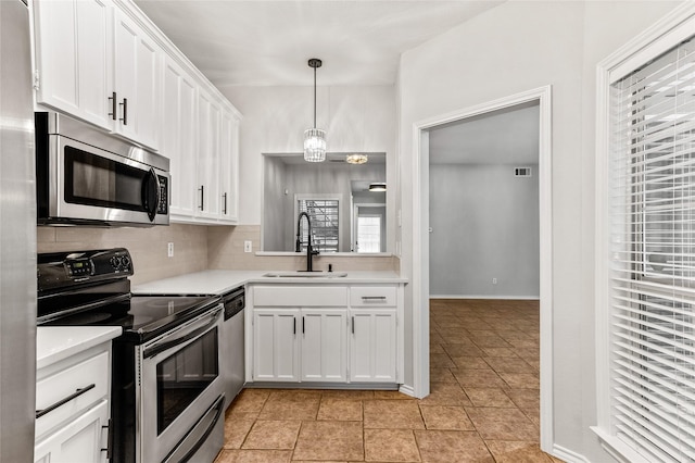 kitchen with hanging light fixtures, white cabinetry, sink, and stainless steel appliances