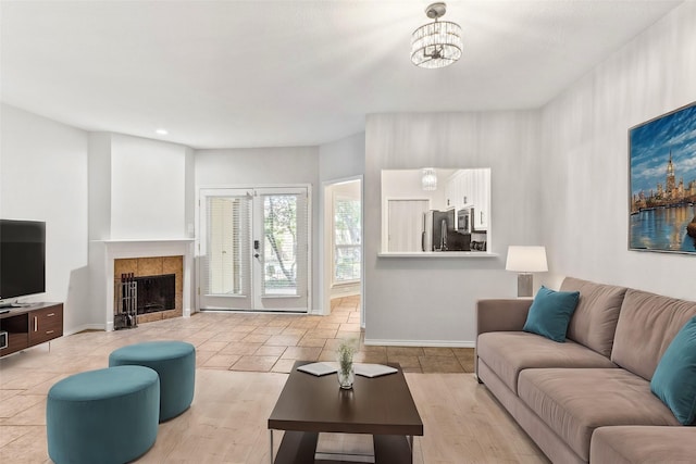 living room featuring a fireplace, light wood-type flooring, and an inviting chandelier