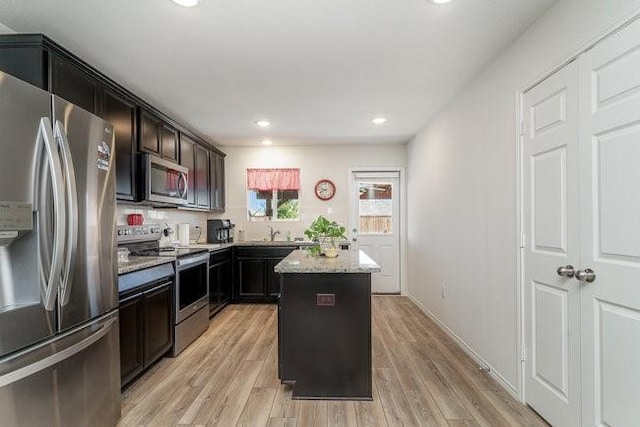 kitchen featuring a center island, light stone counters, light hardwood / wood-style floors, and appliances with stainless steel finishes