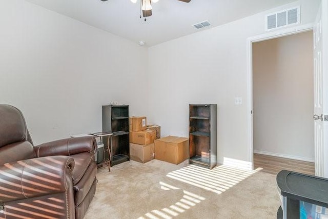 living area featuring ceiling fan and light colored carpet