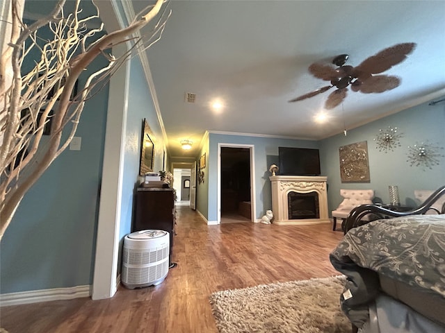 bedroom featuring ceiling fan, crown molding, hardwood / wood-style flooring, a spacious closet, and a closet