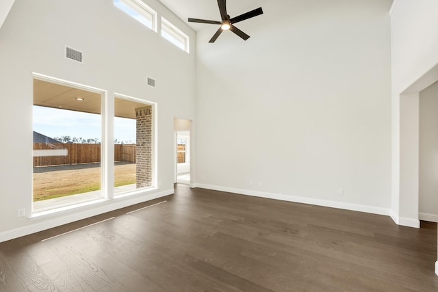 unfurnished living room featuring ceiling fan, a high ceiling, and dark wood-type flooring