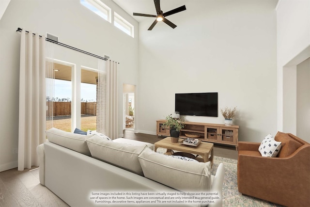 living room featuring light wood-type flooring, a high ceiling, and ceiling fan