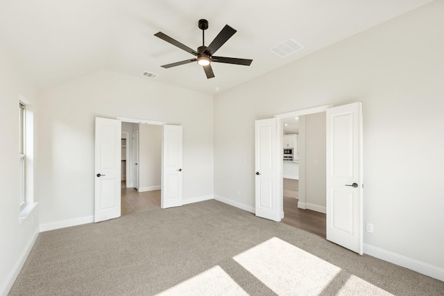 unfurnished bedroom with ceiling fan, light colored carpet, and vaulted ceiling