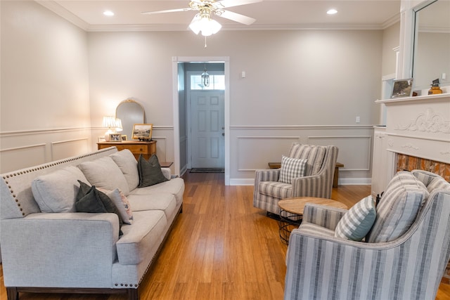 living room featuring ceiling fan, ornamental molding, and light hardwood / wood-style floors