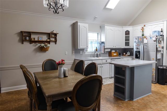 dining room featuring light tile patterned floors, a chandelier, sink, lofted ceiling, and ornamental molding