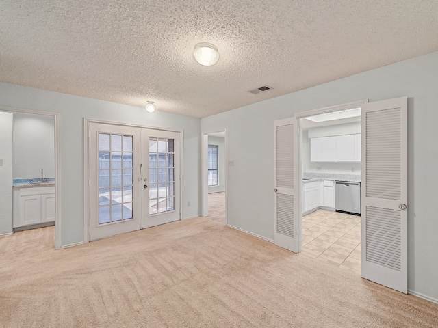 carpeted spare room with french doors, a textured ceiling, and sink