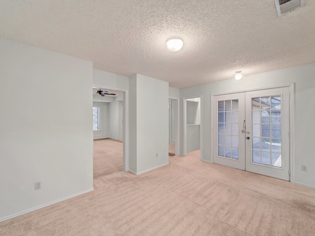 unfurnished room featuring light carpet, french doors, a textured ceiling, and ceiling fan